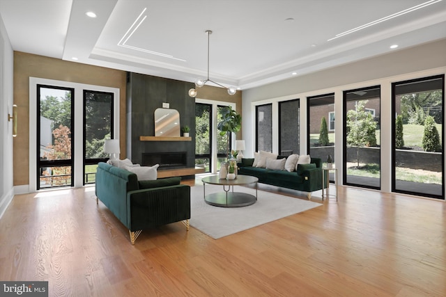 living room with a wealth of natural light, a large fireplace, and light wood-type flooring