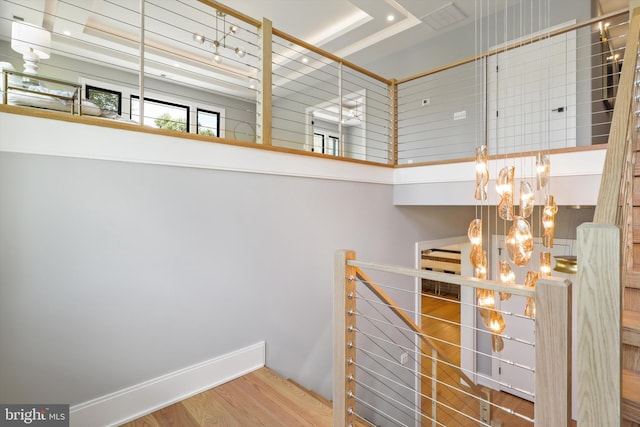 stairway with wood-type flooring and a tray ceiling