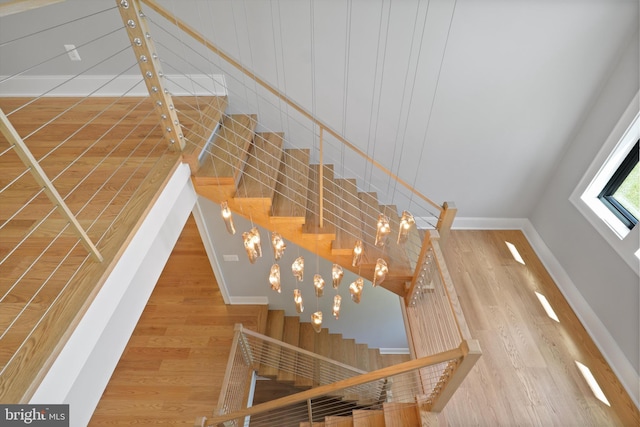 stairway with wood-type flooring and an inviting chandelier