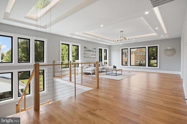 interior space featuring a raised ceiling, light wood-type flooring, and an inviting chandelier