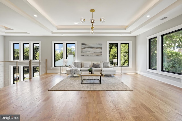 living room featuring visible vents, baseboards, a tray ceiling, wood finished floors, and a notable chandelier