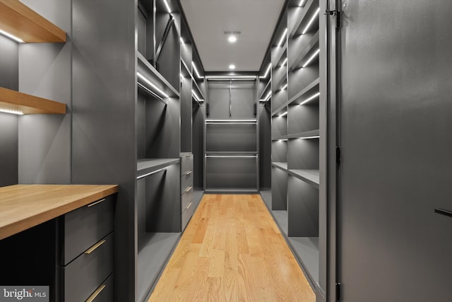 walk in closet with light hardwood / wood-style floors