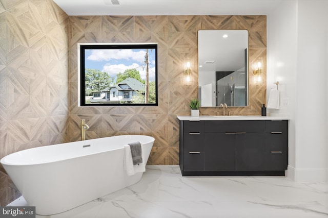 full bathroom with marble finish floor, vanity, and a freestanding tub