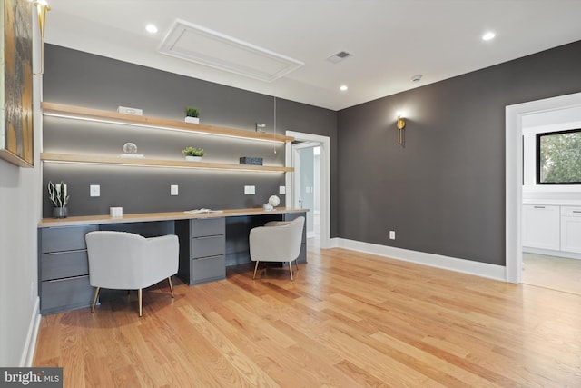 office space with visible vents, light wood-style floors, attic access, and built in desk