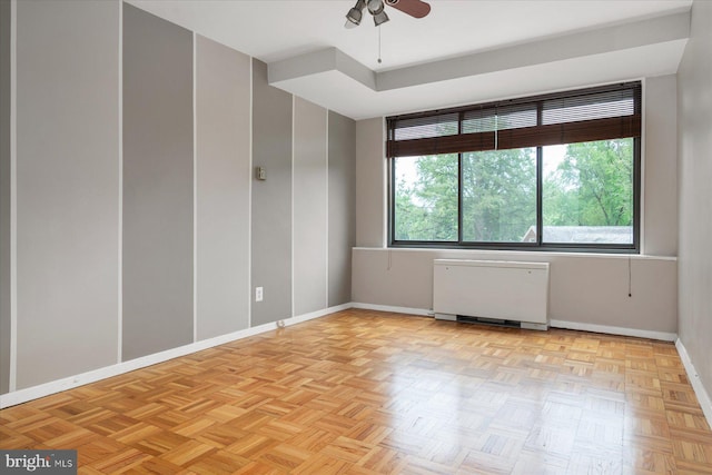 spare room with ceiling fan, radiator heating unit, and light parquet flooring