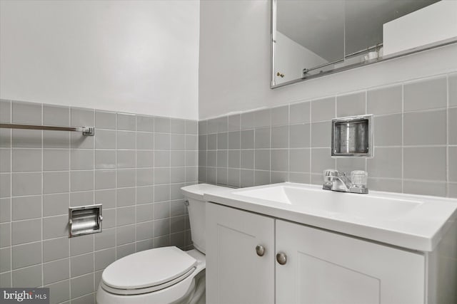 bathroom with vanity, toilet, and tile walls