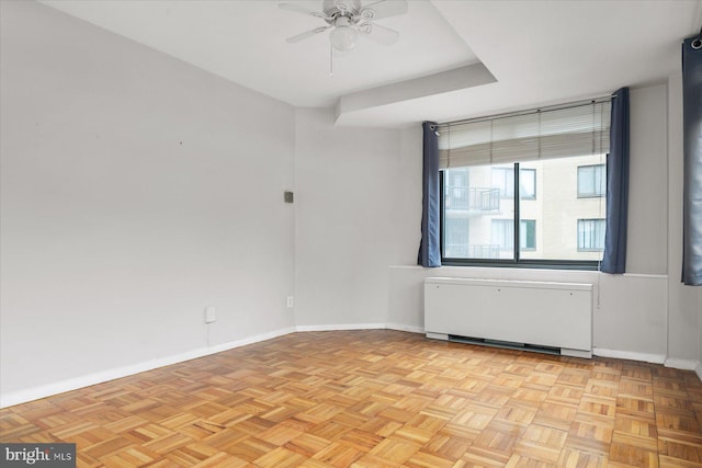 spare room featuring light parquet floors, radiator, and ceiling fan