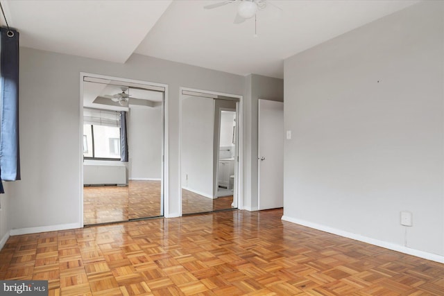 unfurnished bedroom featuring multiple closets, ceiling fan, and light parquet floors