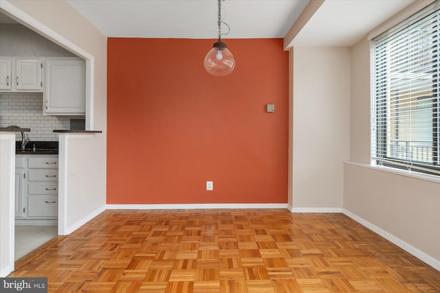 unfurnished dining area featuring plenty of natural light, sink, and light parquet flooring