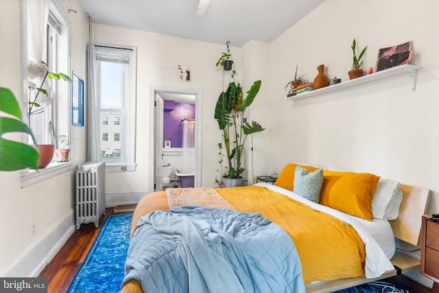 bedroom featuring radiator, multiple windows, baseboards, and wood finished floors