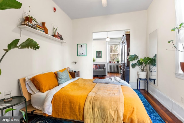 bedroom with radiator, baseboards, and wood finished floors