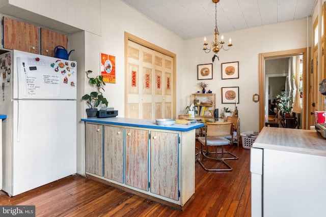 kitchen with light countertops, hanging light fixtures, freestanding refrigerator, dark wood finished floors, and an inviting chandelier