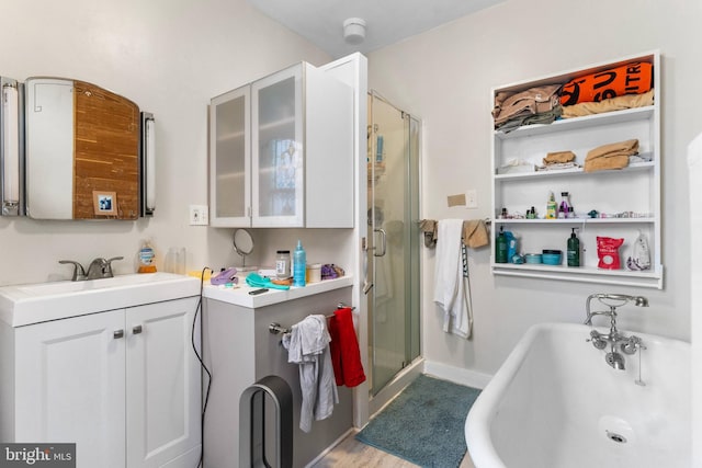 full bath featuring a stall shower, a freestanding tub, vanity, and baseboards