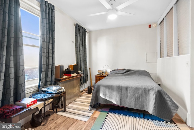 bedroom featuring a ceiling fan, multiple windows, and wood finished floors