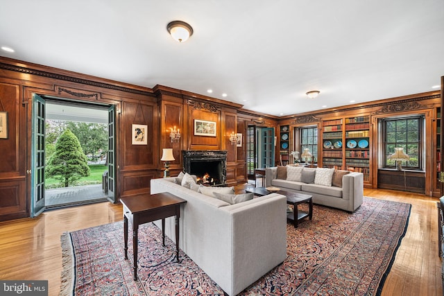 living room featuring crown molding, wooden walls, a fireplace, and light wood-type flooring
