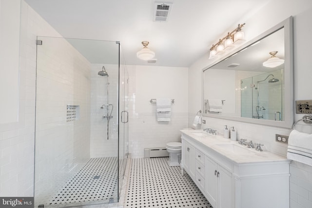 full bath featuring double vanity, a stall shower, visible vents, tile walls, and a sink
