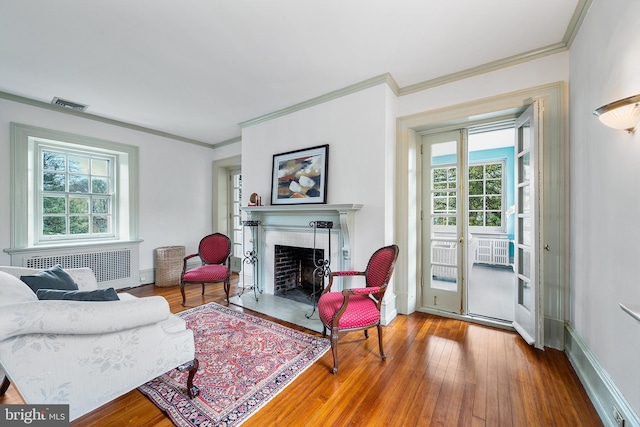 living area featuring visible vents, radiator heating unit, wood-type flooring, and a fireplace with flush hearth