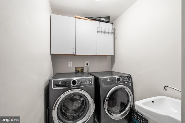clothes washing area with a sink, cabinet space, and separate washer and dryer