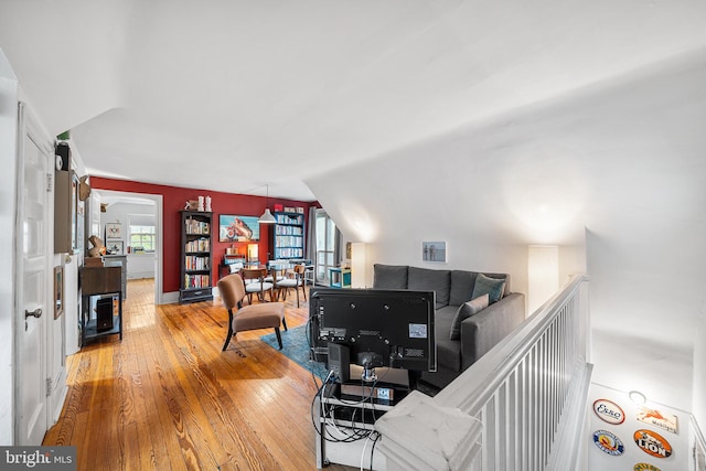 living room featuring wood-type flooring, baseboards, lofted ceiling, and a healthy amount of sunlight