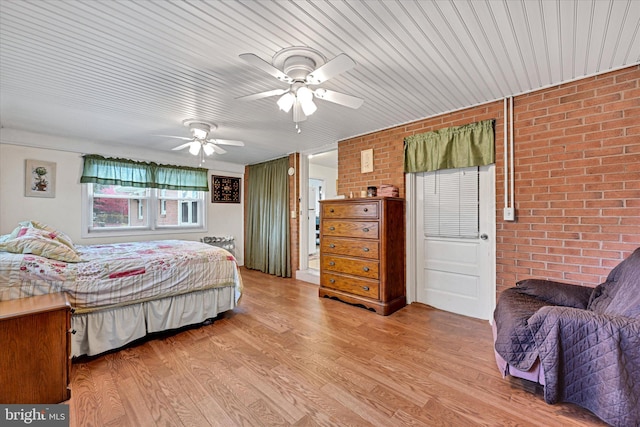 bedroom with ceiling fan, brick wall, and light wood-type flooring