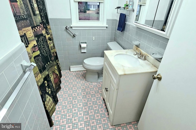 bathroom with vanity, toilet, and tile walls