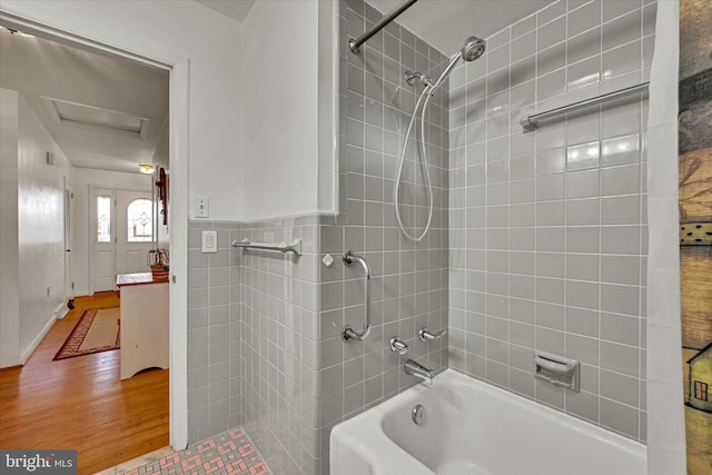 bathroom featuring tiled shower / bath combo, hardwood / wood-style flooring, and tile walls