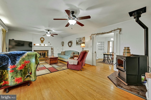 living room featuring ceiling fan, light wood-type flooring, and a wood stove