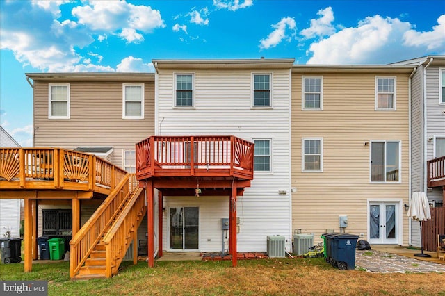 rear view of house featuring a deck, central air condition unit, and a yard