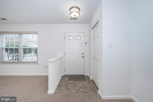 carpeted entrance foyer with a textured ceiling