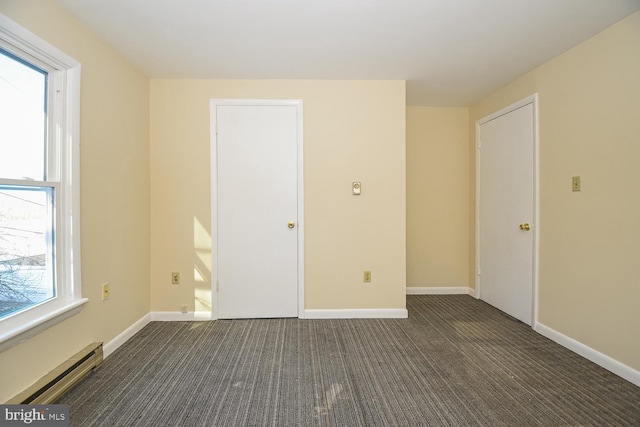 spare room with dark colored carpet and a baseboard radiator