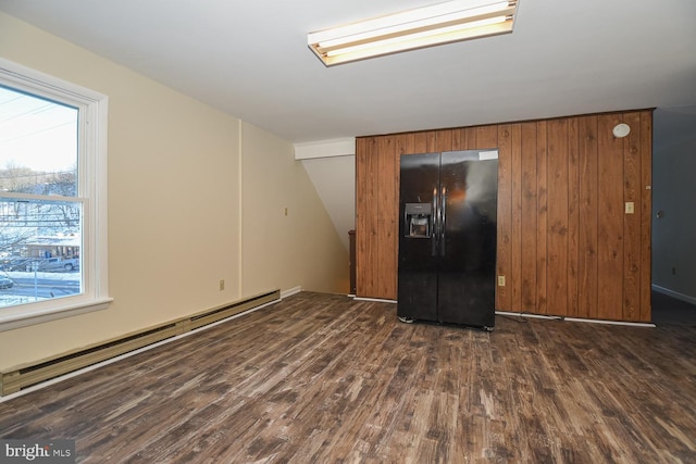 unfurnished room featuring vaulted ceiling, wooden walls, a baseboard radiator, and dark hardwood / wood-style floors