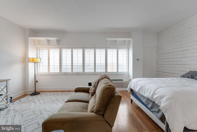 bedroom featuring hardwood / wood-style floors, an AC wall unit, and multiple windows