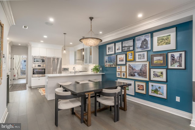 dining room featuring dark hardwood / wood-style flooring, ornamental molding, and sink