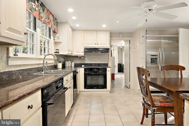 kitchen with backsplash, stainless steel built in refrigerator, sink, dark stone countertops, and oven