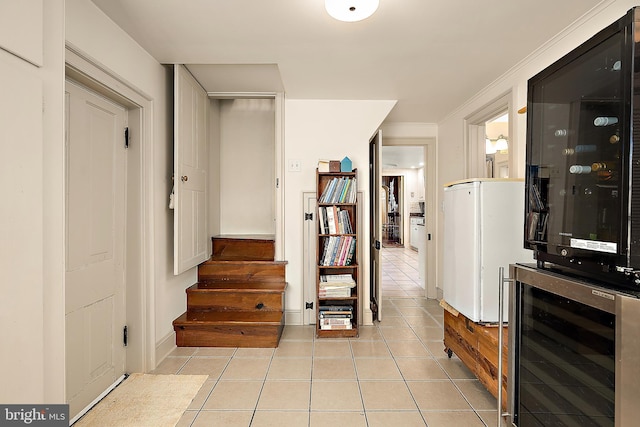 hall with light tile patterned floors, wine cooler, and crown molding