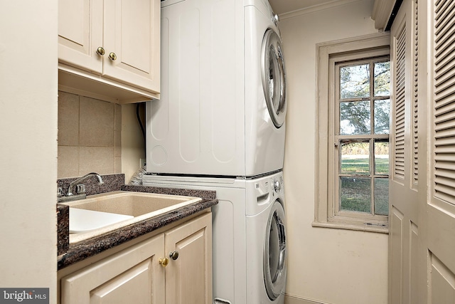 washroom featuring cabinets, stacked washer and dryer, and sink