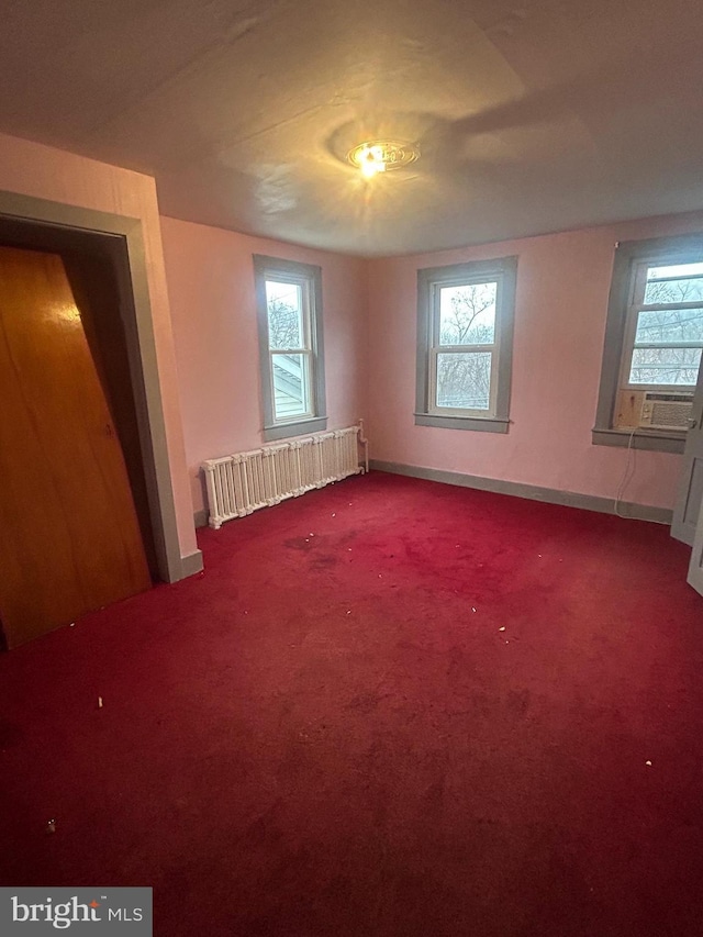 unfurnished bedroom featuring cooling unit, radiator heating unit, and carpet