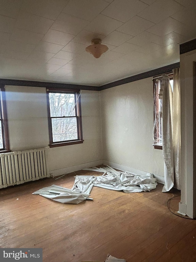 spare room featuring radiator heating unit and hardwood / wood-style floors