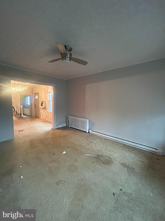 unfurnished room with concrete flooring, radiator, ceiling fan, and a baseboard radiator