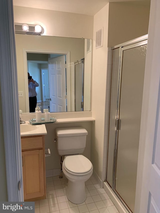 bathroom featuring tile patterned floors, vanity, toilet, and walk in shower