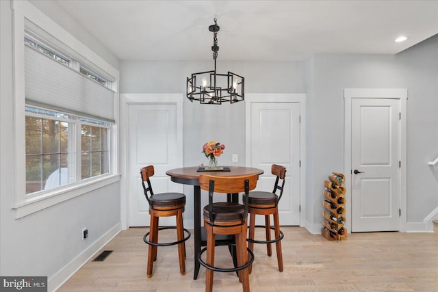 dining space with light hardwood / wood-style flooring and a notable chandelier