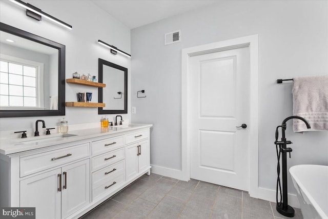 bathroom featuring tile patterned flooring, a bath, and vanity