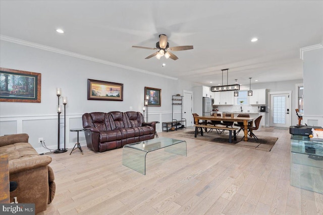 living room featuring light hardwood / wood-style flooring, ceiling fan, and ornamental molding