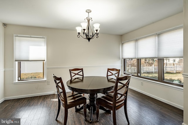 dining space featuring dark wood-type flooring and a notable chandelier