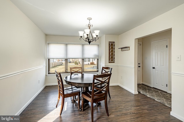 dining space with dark hardwood / wood-style floors and an inviting chandelier