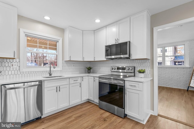 kitchen with white cabinets, appliances with stainless steel finishes, a healthy amount of sunlight, and sink