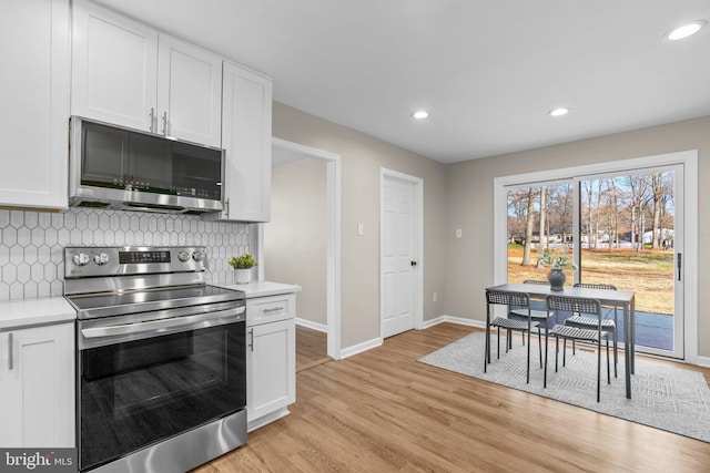 kitchen featuring backsplash, white cabinetry, light hardwood / wood-style flooring, and stainless steel appliances