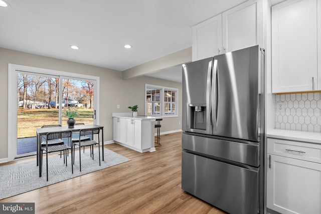 kitchen with stainless steel fridge with ice dispenser, white cabinetry, and plenty of natural light