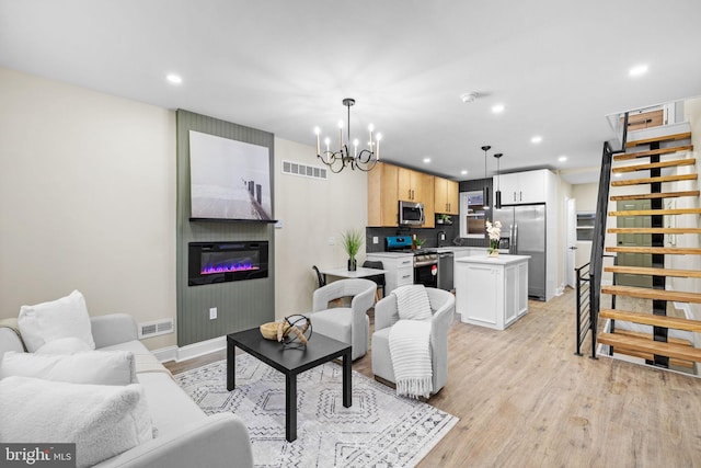 living room with a chandelier, sink, a fireplace, and light hardwood / wood-style flooring