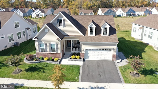 cape cod house featuring covered porch, a garage, and a front yard